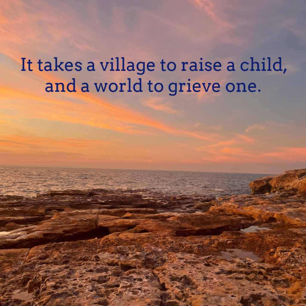 Sunset over a rocky shore and ocean. Text reads It takes a village to raise a child, and a world to grieve one.