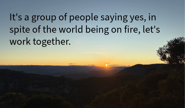 Sunset over hills. Text reads "It's a group of people saying yes, in spite of the world being on fire, let's work together."
